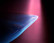 Un faisceau violet venant du haut produit une lueur bleue autour d'un modèle de la navette spatiale